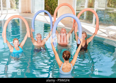 Senior Group sta facendo ginnastica in acqua con piscina a base di noodle in piscina Foto Stock