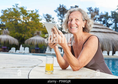 Donna felice utilizzando computer tablet in piscina termale durante la vacanza di wellness Foto Stock