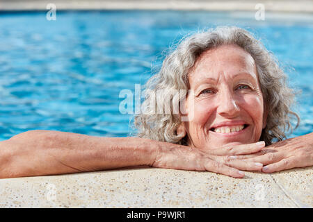 Vitale donna senior sul bordo della piscina in una piscina esterna o su una vacanza di benessere Foto Stock
