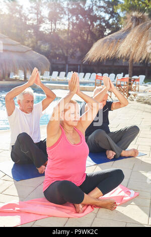 Gli anziani di fare un esercizio in corso di yoga in piscina presso il Wellness Hotel Foto Stock