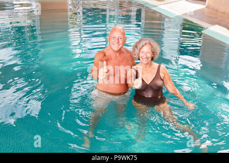 Di vitale importanza coppia senior si rilassa in piscina con il pollice in alto Foto Stock