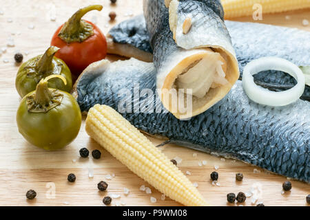 Acqua salata di pesce marinato, antipasto freddo. Aringhe marinate filetto sul tagliere di legno Foto Stock