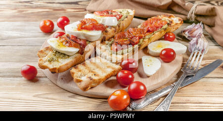Bruschetta con pomodori al forno e mozzarella. Cucina mediterranea. Una gustosa prima colazione. Banner di cibo Foto Stock