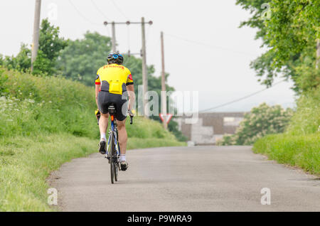 Ciclista maschio ciclismo su uno stretto vicolo del paese in Inghilterra, Regno Unito Foto Stock