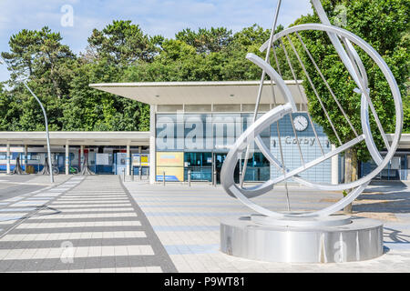 Piazzale davanti all' edificio del terminal della stazione ferroviaria a Corby, Inghilterra, con una contemporanea scultura in acciaio in primo piano (perché C Foto Stock