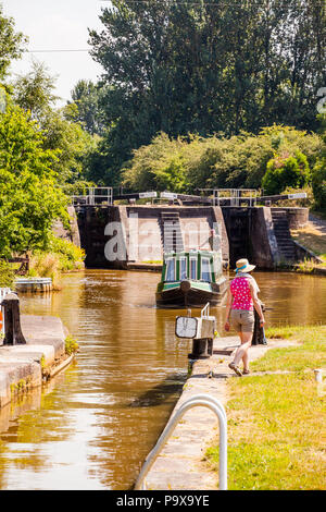 Canal narrowboat che passa attraverso chiuse sul canale Trent e Mersey mentre passa attraverso il villaggio di Wheelock Cheshire Inghilterra Foto Stock