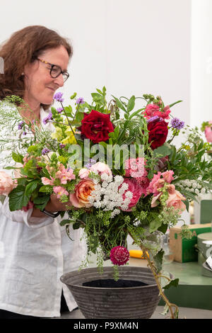 Donna su una composizione floreale in stallo con un mazzo di fiori in corrispondenza di RHS Hampton Court flower show 2018. Londra. Regno Unito Foto Stock