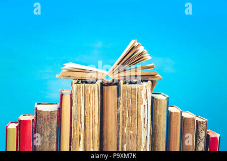 Fila di vecchi libri con aperto su uno scaffale di legno, dai toni rétro Foto Stock
