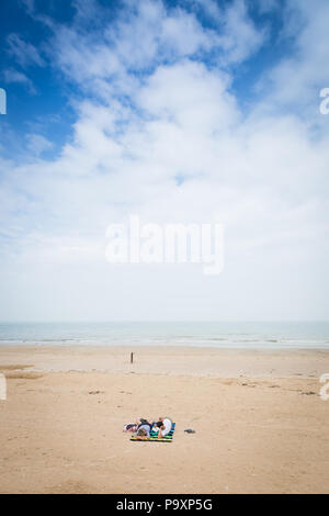 Due persone a prendere il sole su una vasta spiaggia vuota, Normandia, Francia Foto Stock