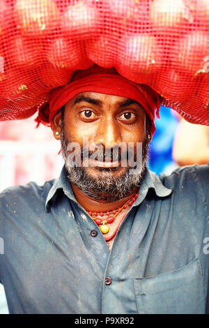 Testa e spalle ritratto di metà uomo adulto con barba e baffi che trasportano il sacco sulla testa, Kerala, India Foto Stock