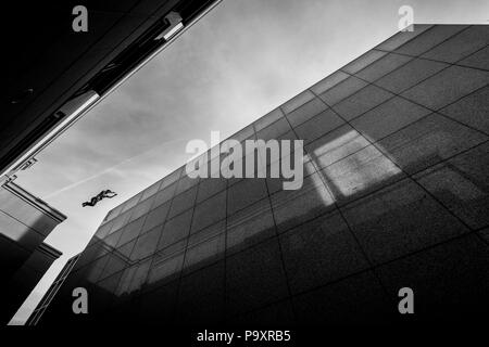 Vista dal basso del maschio atleta di parkour saltando da un tetto a un altro Foto Stock