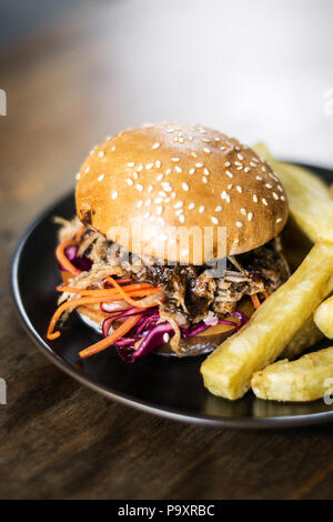 Tirate la carne di maiale e insalata coleslaw sandwich di hamburger con patatine fritte snack pasto Foto Stock
