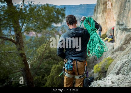 Vista posteriore shot dei maschi di rocciatore fune portante di Cliff, Siurana, Catalogna, Spagna Foto Stock