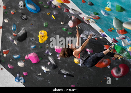 Vista laterale della singola donna avventurose arrampicate su parete strapiombante Foto Stock