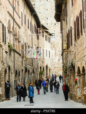 I turisti a San Gimignano, una piccola parete colle medievale cittadina in provincia di Siena, Toscana, Italia del centro-nord. Conosciuta come la città delle belle torri di San Gimignano è famosa per la sua architettura medievale, unica nella conservazione di circa una dozzina delle sue case a torre, che con la sua impostazione di collina e cinta muraria Foto Stock