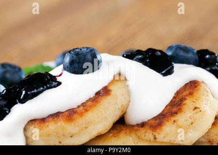 Fritti di ricotta dolci con confettura di mirtilli e mirtillo bacche che serve la cena, primo piano Foto Stock