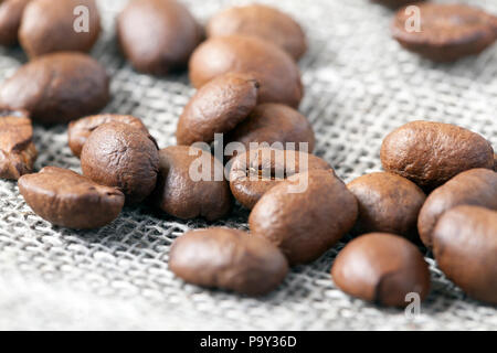 Chicchi di caffè tostati su lino grezzo materiale durante la vendita nel negozio, photo closeup Foto Stock