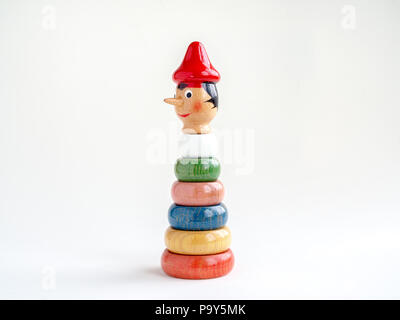 Pinocchio in legno testa di bambola sulla pila di legno colorato gioco donut isolati su sfondo bianco. Foto Stock