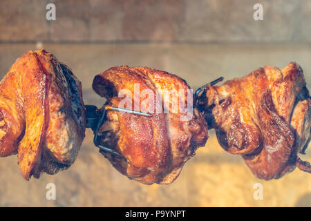 Appetitose grigliate di carne di maiale allo spiedo. Gamba di arrosto di maiale sul barbecue tradizionale. Preparato di una ram maiale cotto con la carne di maiale Street cibo intero maiale di torrefazione del fuso a snodo sul grill a carbone. Foto Stock