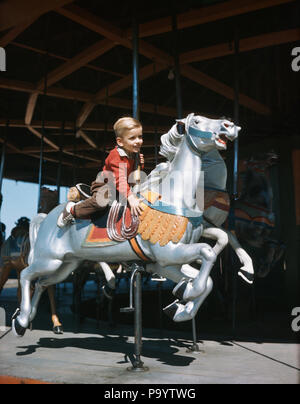 Anni Cinquanta sorridenti Little Boy a cavallo al galoppo Giostra cavalli sul Merry Go Round - kj433 DEB001 HARS bionda cavalcare cavalli vacanza stile di vita la gioia di velocità Copia evento spazio persone i bambini a tutta lunghezza persone maschi ENTERTAINMENT AMERICANA colorato tema RIDER AMUSEMENT sogni di felicità mammiferi viaggio avventura Divertimento parchi ricreativi giostra merry-go-round scolpiti Merry Go Round giostre fantasia di fuga elegante DEB001 Fiere equina eccitante novellame mammifero montato RIDES SCULTURE IN LEGNO sculture in legno giovane etnia caucasica al galoppo in vecchio stile Foto Stock