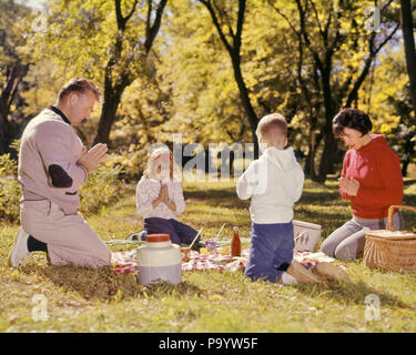 Negli anni sessanta la famiglia inginocchiati intorno al picnic IN ERBA giornata autunnale dicendo grazia preghiera - KR9415 HAR001 HARS madri di colore vecchio tempo NOSTALGIA OLD FASHION capretti equilibrio figli famiglie gioia lifestyle religione celebrazione femmine sposato preghiera coniuge rurale mariti dicendo spazio copia a tutta lunghezza LADIES figlie persone cura maschi grazia serenità spiritualità padri inginocchiati felicità forza papà collegamento dicendo grazia novellame MID-adulto metà uomo adulto a metà donna adulta mamme stare insieme mogli etnia caucasica HAR001 in vecchio stile Foto Stock