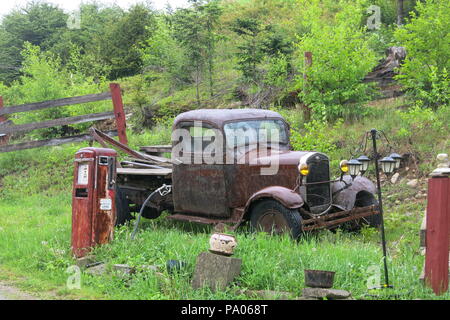 Questa antica Ford a trainare il carrello e la vecchia pompa di benzina, abbandonati in campagna, fare una scena vintage e ricordi di un epoca passata. Foto Stock