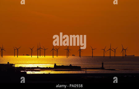 Il sole tramonta oltre la banca Burbo Offshore Wind Farm sul fiume Mersey dietro Fort Roick semaforico e New Brighton Lighthouse. Foto Stock