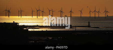 Il sole tramonta oltre la banca Burbo Offshore Wind Farm sul fiume Mersey dietro Fort Roick semaforico e New Brighton Lighthouse. Foto Stock