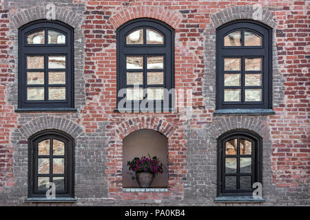 Frammento di parete del Castello di Mir, fatta di mattoni rossi con finestre e una nicchia con fiori. Foto Stock