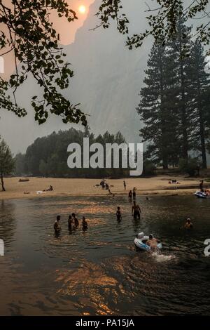 Parco Nazionale di Yosemite in California, Stati Uniti d'America. 19 Luglio, 2018. Parco Nazionale di Yosemite visitatori nuotare nel fiume Merced vicino Ponte oscillante sotto pesante fumo e foschia creata dal fuoco Ferguson giovedì 19 luglio, 2018. Il fuoco ha cominciato il 13 luglio e ha bruciato oltre 21.000 acri vicino al parco. Due i vigili del fuoco hanno subito delle lesioni e un vigile del fuoco ha perso la vita. Credito: Tracy Barbutes/ZUMA filo/Alamy Live News Foto Stock