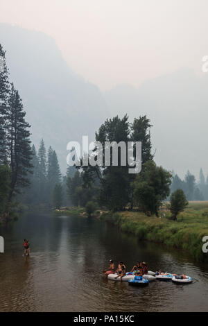 Parco Nazionale di Yosemite in California, Stati Uniti d'America. 19 Luglio, 2018. Parco Nazionale di Yosemite visitatori galleggiante nel fiume Merced vicino Ponte oscillante sotto pesante fumo e foschia creata dal fuoco Ferguson giovedì 19 luglio, 2018. Sotto un cielo terso, Yosemite Falls potrebbe facilmente essere visto dietro il parco i visitatori. Il fuoco ha cominciato il 13 luglio e ha bruciato oltre 21.000 acri vicino al parco. Due i vigili del fuoco hanno subito delle lesioni e un vigile del fuoco ha perso la vita. Credito: Tracy Barbutes/ZUMA filo/Alamy Live News Foto Stock