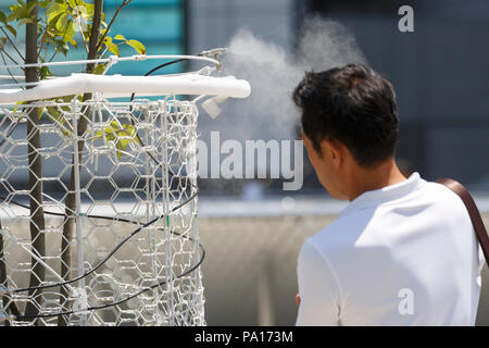 Tokyo, Giappone. Il 20 luglio, 2018. Un uomo cammina sotto acqua atomizzatore per raffreddare fuori se stesso al Tokyo Big Sight sulla luglio 20, 2018 a Tokyo, Giappone. Il caldo ha visto temperature aumento ad alto come 40,7 C gradi in Giappone centrale il mercoledì e l'ondata di caldo è destinato a durare almeno fino alla fine del mese. A livello nazionale oltre diecimila persone sono stati ricoverati in ospedale come risultato del calore. Credito: Rodrigo Reyes Marin/AFLO/Alamy Live News Foto Stock