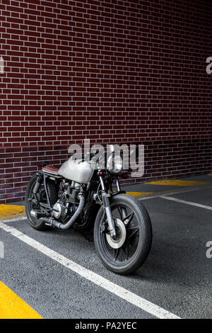 Custom Moto parcheggio nei pressi di un muro di mattoni di edificio delle finanze. Tutto è pronto per il divertimento alla guida della strada vuota su un motociclo in viaggio. Foto Stock