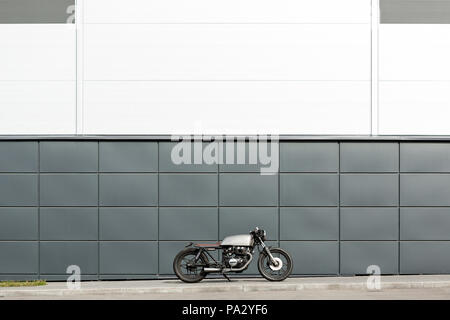 Custom Moto parcheggio vicino al muro grigio delle finanze edificio. Tutto è pronto per il divertimento alla guida della strada vuota su un motociclo in viaggio. C Foto Stock