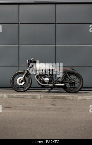 Custom Moto parcheggio vicino al muro grigio di edilizia industriale. Tutto è pronto per il divertimento alla guida della strada vuota su un motociclo in viaggio Foto Stock