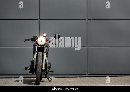 Custom Moto parcheggio vicino al muro grigio di edilizia industriale. Tutto è pronto per il divertimento alla guida della strada vuota su una moto tour journe Foto Stock