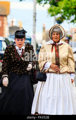 Due le donne anziane, 60s, vestito in abito vittoriano durante il Broadstairs Dickens week festival. Camminando verso il visualizzatore. Uno in abito nero. Foto Stock