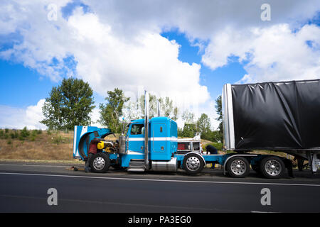 I guidatori di autocarri riparazione big rig cofano blu semi carrello con cappa aperta la rottura si è verificata durante la consegna della merce e portare coperte caricati semi Foto Stock