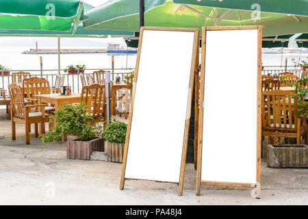 Due lavagna vuota contro di sedie a sdraio e ombrelloni Foto Stock