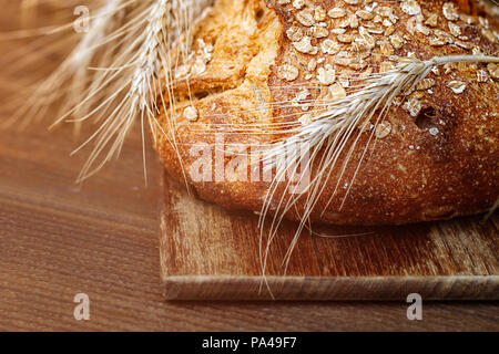 Panetteria pane su un tavolo di legno. Pane e un covone di grano. Foto Stock