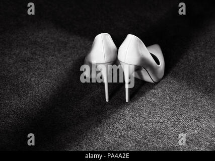 Weddihg scarpe bianco isolato in uno sfondo scuro. Foto in bianco e nero Foto Stock