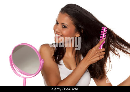 Giovane donna felice pettinare i suoi capelli lunghi Foto Stock