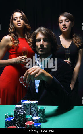 L uomo alla roulette tavolo circondato da belle donne Foto Stock