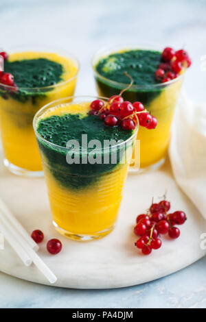 Due colori freschi frullati in bicchieri con frutti di bosco freschi. orange succo di banana con spirulina in polvere. detox prima colazione. Il mangiare sano Foto Stock