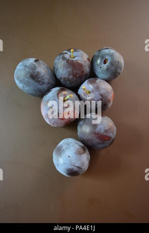 Prugne strappate fresche su sfondo marrone opaco. Foto Stock