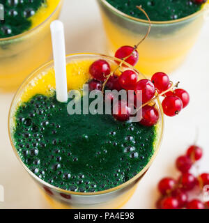 Due colori freschi frullati in bicchieri con frutti di bosco freschi. orange succo di banana con spirulina in polvere. detox prima colazione. Il mangiare sano Foto Stock