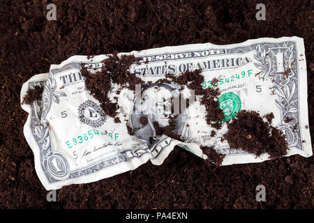 Crumpled un dollaro statunitense giacenti su uno sfondo di colore scuro del suolo, closeup, su una cassa di banconota versata messa a terra Foto Stock