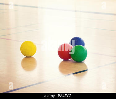 Impostare il gruppo di quattro coloratissimi palle sportive la posa sul pavimento in palestra, una sfera separato dagli altri, la nozione di individuo a differenza di altri, divertente attività Foto Stock