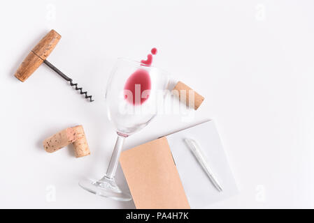 Degustazione di vini notebook con penna. Un cavatappi e bicchiere e tappi su bianco con copia spazio. Foto Stock