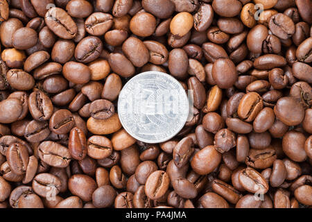 Bella e profumata frittura di grani interi di caffè, closeup, vista dall'alto, sul caffè si trova la retromarcia verso l'alto moneta americana in un quarto di dollaro Foto Stock